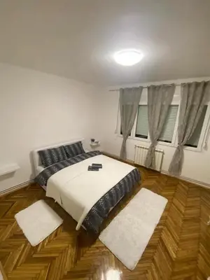 a bedroom with a bed and two rugs on the floor at Apartment Pionir Grim in Belgrade