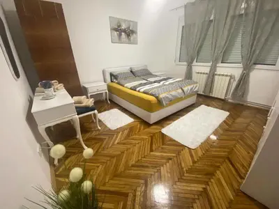 a bedroom with a bed and a wooden floor at Apartment Pionir Grim in Belgrade