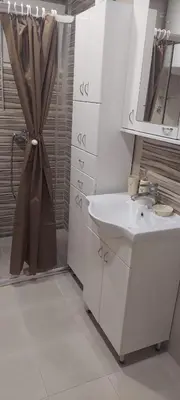 a white bathroom with a sink and a shower at Apartment Pionir Grim in Belgrade