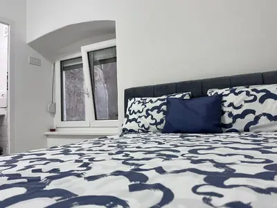 a bed with a blue and white comforter and a window at RiverScapeMoments Studio in Belgrade