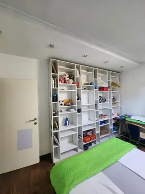 a bedroom with white shelves and a green rug at Wenge in Karaburma