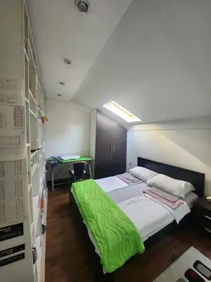 a bedroom with a bed with a green blanket on it at Wenge in Karaburma