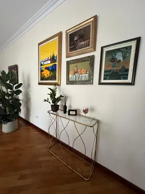 a room with a white wall with paintings and a table at Top secret 24 in Belgrade