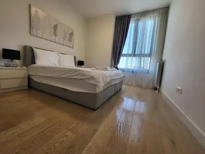 a bedroom with a large bed and a wooden floor at BW Waterfront LUX apartment, parking free in Sajmište