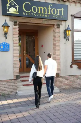 a man and a woman walking into a restaurant at Comfort Lodge in Stari Banovci
