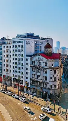 a large white building with cars parked in front of it at Lumière Hotel Pool & SPA in Belgrade