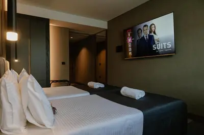 two beds in a hotel room with a tv on the wall at Lumière Hotel Pool & SPA in Belgrade