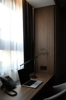 a desk with a laptop computer and a phone on it at Lumière Hotel Pool & SPA in Belgrade