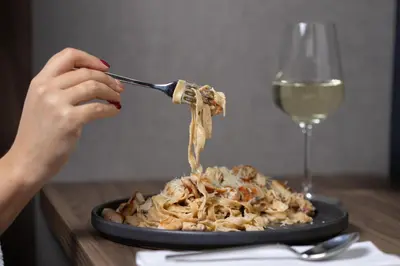 a person is eating pasta with a glass of wine at Lumière Hotel Pool & SPA in Belgrade
