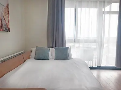 a bedroom with a large white bed with blue pillows at Panoramic View Lux Apartment BW in Sajmište