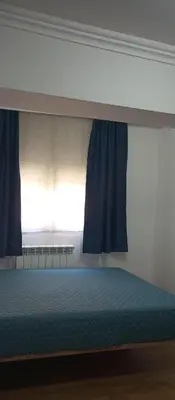 a bed in a bedroom with blue curtains and a window at Airpot MD rooms 1 in Belgrade
