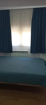 a bed in a bedroom with blue curtains and a window at Airpot MD rooms 1 in Belgrade