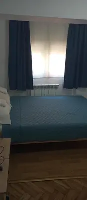 a bed in a room with a window with blue curtains at Airpot MD rooms 1 in Belgrade