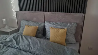 a bed with blue and yellow pillows on it at Apartman Lola in Novi Grad