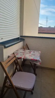 a table and chairs on a balcony with a window at Apartman Lola in Novi Grad