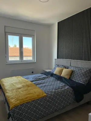 a bedroom with a bed and two windows at Apartman Lola in Novi Grad