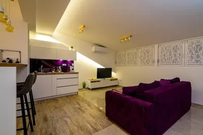 a living room with a purple couch and a kitchen at Boom Spa 1 Belgrade Apartments in Fontana
