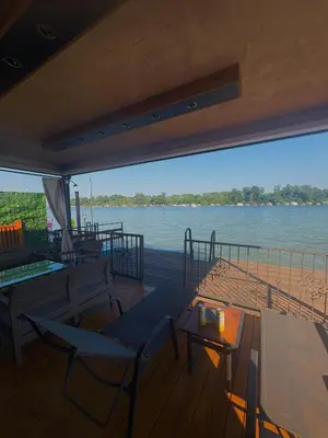 a deck with chairs and tables and a view of the water at Santa Barbara River in Belgrade