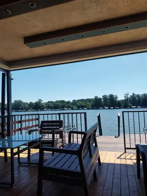 a deck with chairs and tables and a view of the water at Santa Barbara River in Belgrade