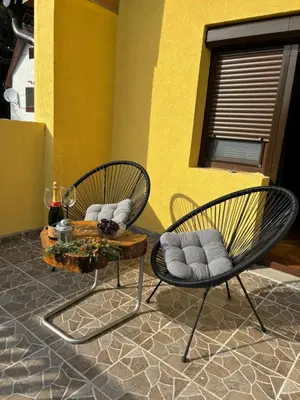 two chairs and a table in front of a yellow wall at Kućica u pesku in Novi Vladimirovac
