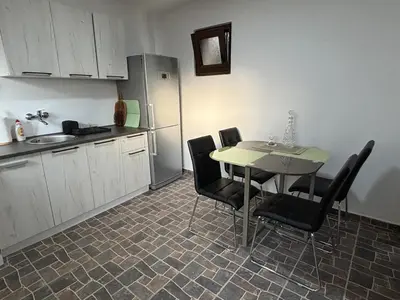 a kitchen with a table and chairs and a refrigerator at Kućica u pesku in Novi Vladimirovac