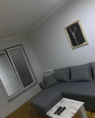 a living room with a blue couch and a table at Stan na dan in Voždovac