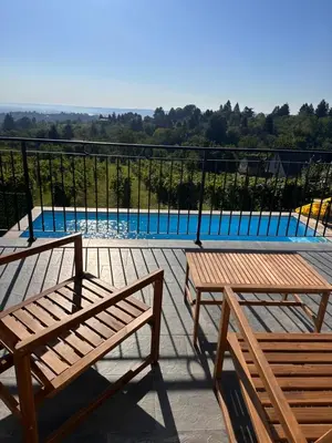 two wooden benches on a balcony with a swimming pool at Vila Vista Verde in Zaklopača