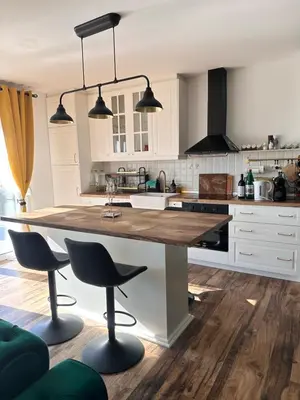 a kitchen with white cabinets and a large island with bar stools at Vila Vista Verde in Zaklopača