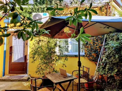 a patio with a table and an umbrella and a laptop at Zemun Riverside in Zemun