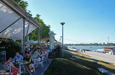 a group of people sitting at tables near the beach at Zemun Riverside in Zemun