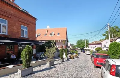 a cobblestone street with cars parked next to buildings at Zemun Riverside in Zemun
