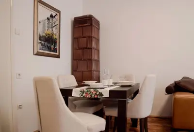a dining room with a black table and white chairs at Classy and cozy near Tasmajdan park and Flower Piazza in Belgrade