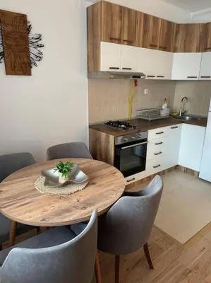 a small kitchen with a wooden table and chairs at Caravaggio Apartman in Mladenovac