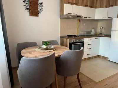 a small kitchen with a wooden table and chairs at Caravaggio Apartman in Mladenovac
