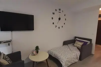 a living room with a couch and a clock on the wall at BRAND NEW Entire Place in CENTER of ZEMUN in Belgrade