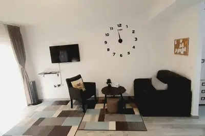 a living room with two chairs and a clock on the wall at BRAND NEW Entire Place in CENTER of ZEMUN in Belgrade