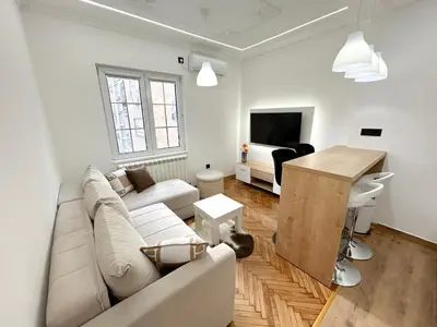 a white living room with a couch and a table at Central Elegance in Belgrade