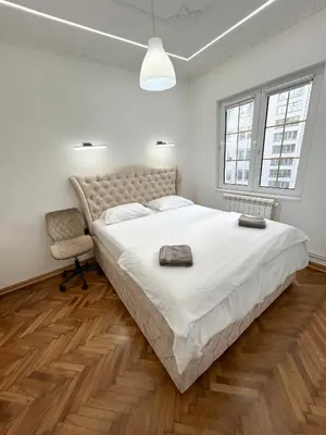 a white bedroom with a large bed and a chair at Central Elegance in Belgrade