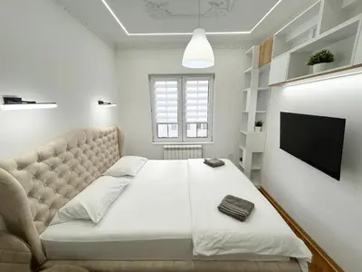 a bedroom with a large white bed with a couch at Central Elegance in Belgrade