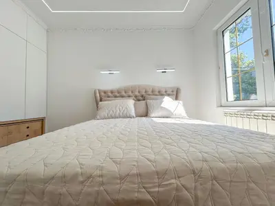a large bed in a white room with a window at Central Elegance in Belgrade
