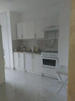 a kitchen with white cabinets and a stove top oven at Toni apartments in Voždovac