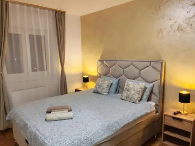 a bedroom with a bed and two lamps and a window at Golden dream apartman in Pančevo
