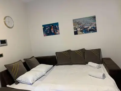 a bed with two pillows and a clock on the wall at Belgrade Center Apartment Studio in Belgrade