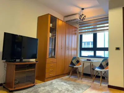 a living room with a tv and a table with chairs at Belgrade Center Apartment Studio in Belgrade