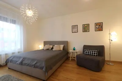 a bedroom with a bed and a chair and a chandelier at Savada Delta City - stan na dan Novi Beograd in Belgrade
