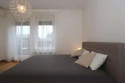 a bedroom with a large bed with a chandelier at Savada Delta City - stan na dan Novi Beograd in Belgrade