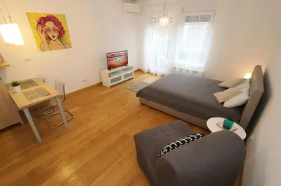 a bedroom with a bed and a couch and a television at Savada Delta City - stan na dan Novi Beograd in Belgrade