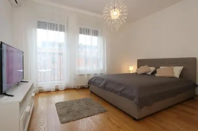 a bedroom with a bed and a television and a chandelier at Savada Delta City - stan na dan Novi Beograd in Belgrade