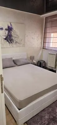 a white bed in a bedroom with a painting on the wall at Lux apartmann in Karaburma