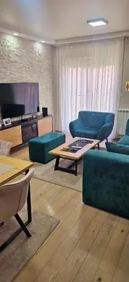 a living room with blue couches and a flat screen tv at Lux apartmann in Karaburma